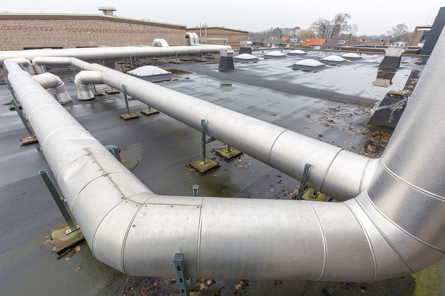 Metal pipes for ventilation system on flat roof of school building. I took this photo on top of the high school where I work. These metal pipes are transporting the used air from the classrooms to outside. At the same time fresh air is coming in the same rooms so the school pupils stay healthy and can study more easily.